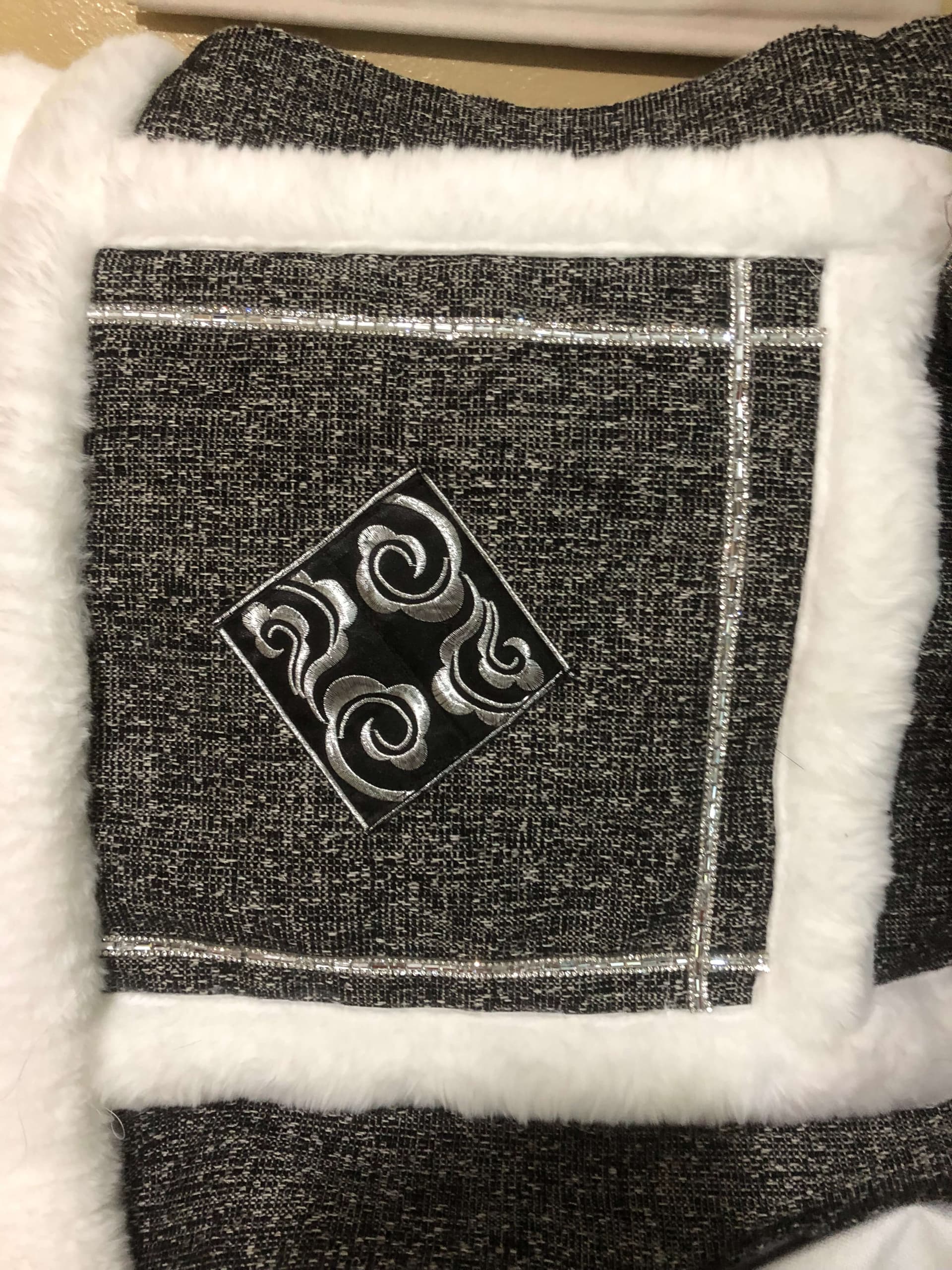 Close-up of charcoal handmade pillow cover with ivory faux-fur trim, rhinestone lines, and silver diamond applique
